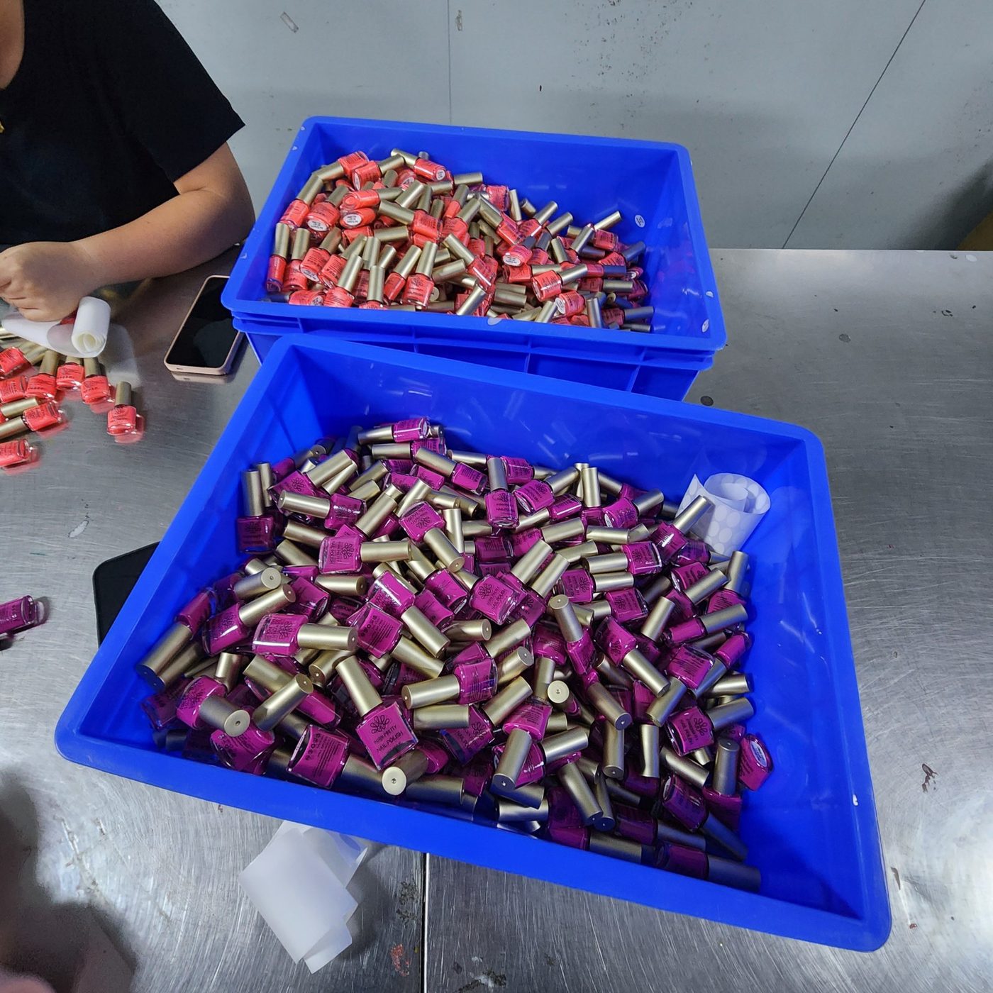 Coral and pink glow in the dark nail polish being labelled on the production line