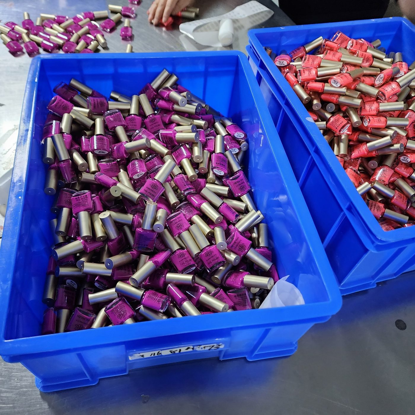 Hot pink glow in the dark nail polish bottles with gold caps in a production crate